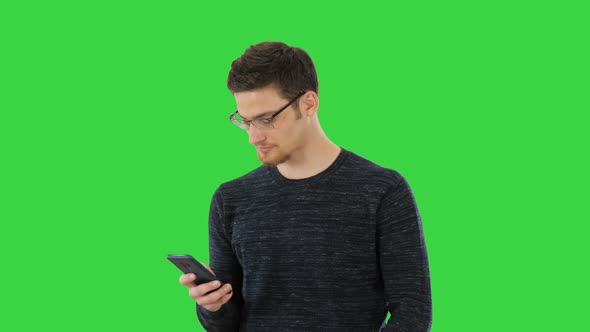 Man with Glasses Suffering with Cough and Using His Phone on a Green Screen, Chroma Key.