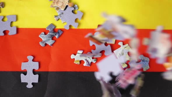 Close-up of colorful jigsaw puzzle pieces falling on the German flag in slow motion