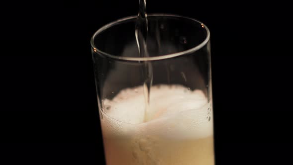 Pouring Beer in Glass From Bottle, Making Foam. Close Up Spinning Full Frame