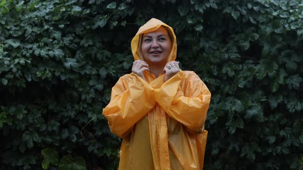 An Attractive Girl Rejoices in the Rain in the Park in the Yellow Pasha