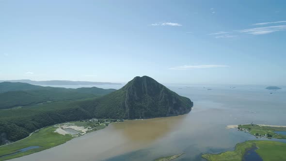 Aerial View of the Tall Mountain Covered By the Forest Towering Over the Empty Valley and Sea on