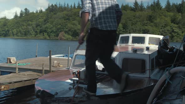 Young man walks onto wood boat bow and checks teak wood trim for fit