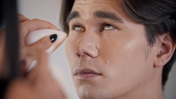 Woman Make Up Artist Applying Concealer on the Face of Male Model with a Pad