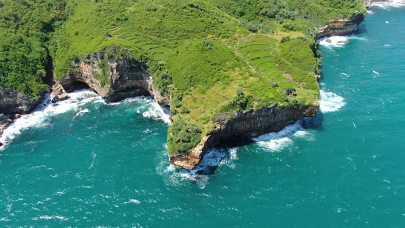 Cliff shoreline of Gesing Beach, turquoise ocean waves hitting rocks, Indonesia