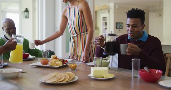 Three generation african american family having breakfast sitting together on dining table at home