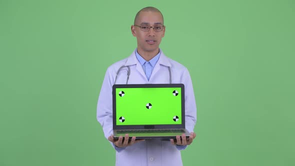 Happy Bald Multi Ethnic Man Doctor Talking While Showing Laptop