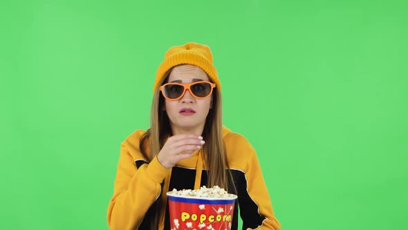 Portrait of Modern Girl in Yellow Hat in 3D Glasses Is Watching a Scary Movie and Eating Popcorn
