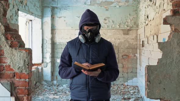 Man in Gas Mask Reading Book in Destroyed Building
