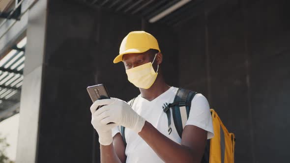 African Food Delivery Man Looking at Smartphone Checking Destination