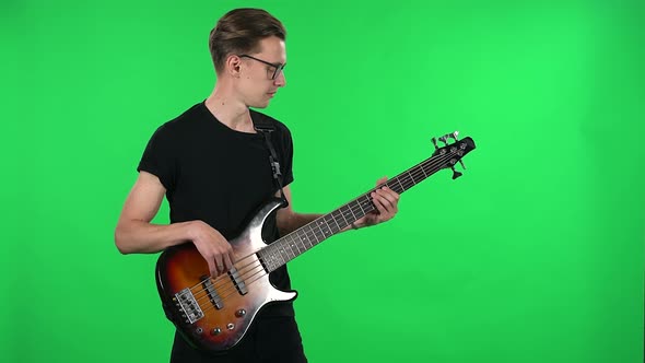 Portrait Professional Musician Playing the Electric Bass. Young Guy with Glasses and a Black T