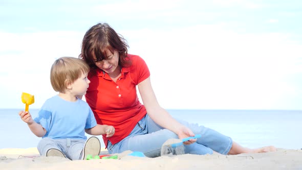 Mother Plays With Little Child On Beach