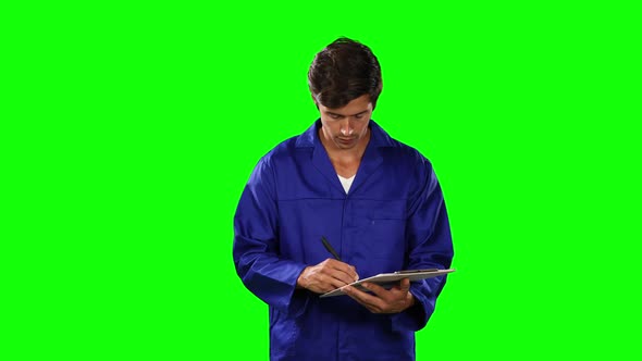 Front view of mechanic taking note with green screen