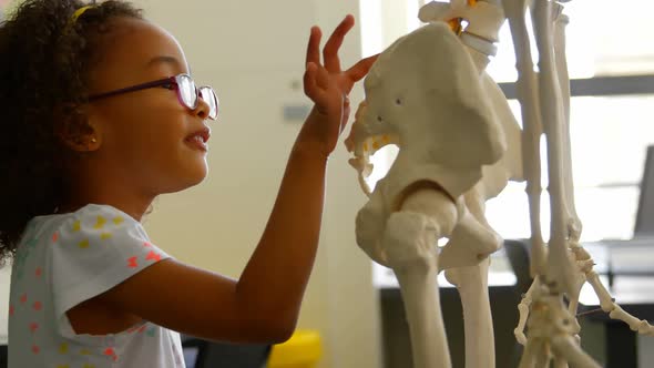 Side view of African american schoolgirl learning human skeleton in classroom at school 4k