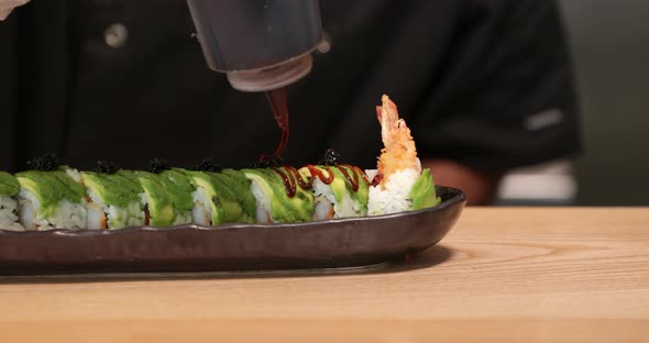 Topping Prepared Shrimp Tempura Sushi Rolls With Eel Sauce - close up panning shot, slow motion