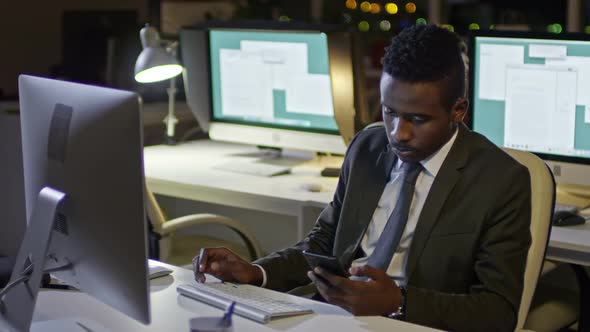 African Office Clerk Working on Computer and Talking on Phone