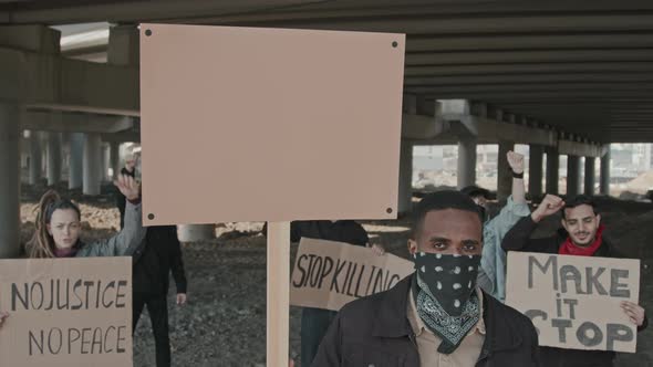 Group of Protesters with Signs under Highway Bridge