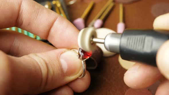 A Professional Jeweler Polishes a Red Gem on a Gold Ring Using a Special Tool