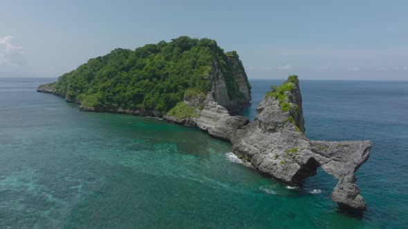 Wild tropical remote island with steep rock cliffs, Nusa Batupadasan, aerial