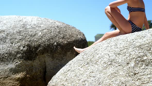 Girl sitting on a rock in the beach 4k