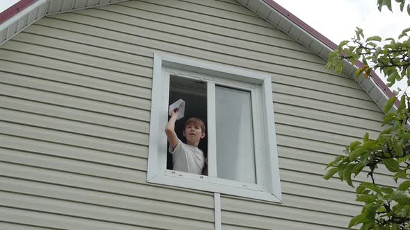 Young Boy Throws a Paper Plane Out of Window alt