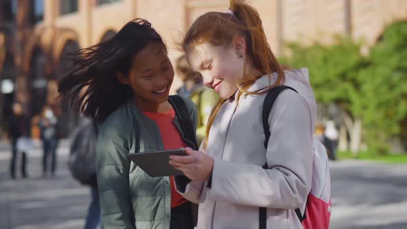 Portrait of Two Diverse Schoolgirls Using Digital Tablet Standing Outdoors