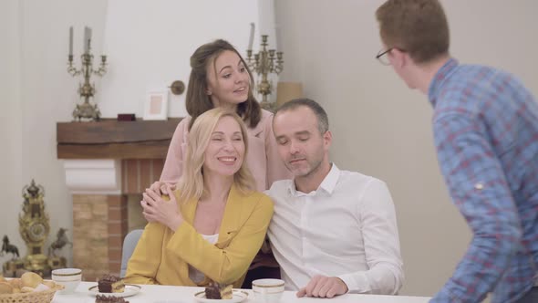 Young Smiling Caucasian Man Adjusting Photo Camera and Joining Family To Take a Photo