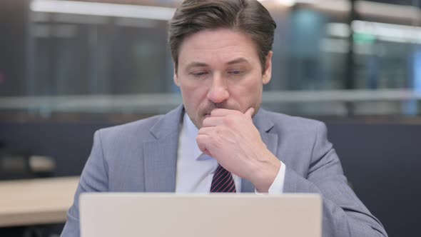 Close Up of Middle Aged Businessman Thinking and Working on Laptop 