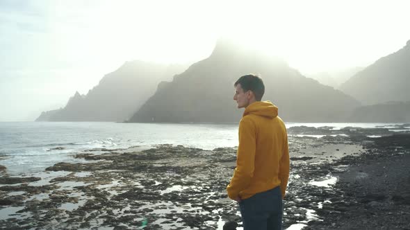 Tourist Man in Yellow Sweatshirt Walks on Volcanic Beach in North of Canary Island Tenerife