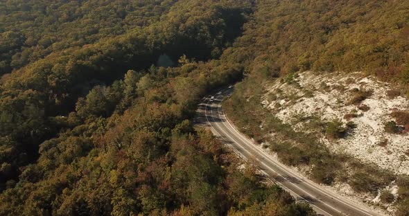 Aerial View of Car Driving Along The Winding Mountain Pass Road Through The Forest Trees. Autumn