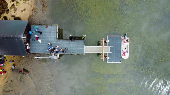 Overhead Shot Of People Standing On Patio Of Unique Small Cottage Built On Water Sea, California