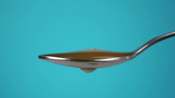 A spoonful of apple cider vinegar on a colored blue background