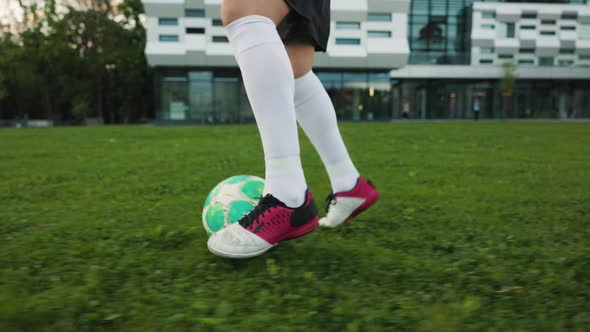 Woman Football Player Trains on the Grass Field in the the Evening Park a Freestyler Leads the Ball