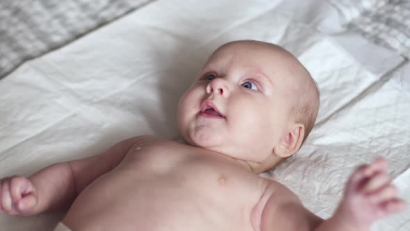 Little Cute Newborn Baby Toddler on Bed Smiles, Happy Maternity Concept