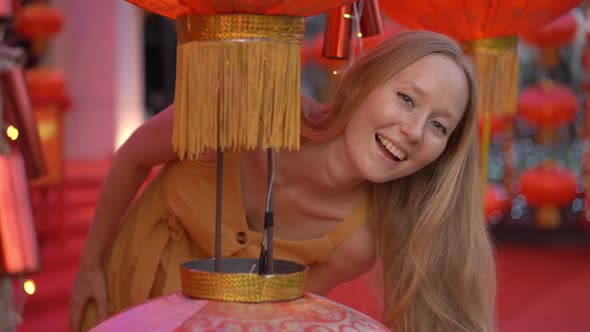 Slowmotion Shot of a Beautiful Young Woman Looks Out From Behind a Red Lantern and Laughs. The