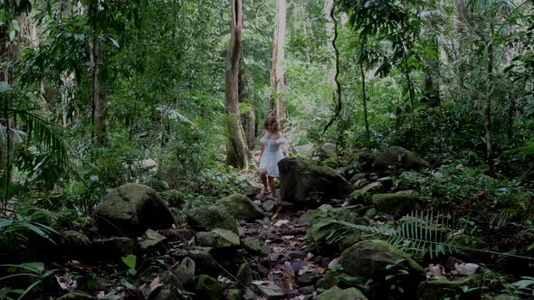 Smiling Woman Walking Barefoot Among Big Moss Stones in Tropical Jungle