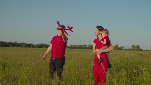 Parents with Kid Playing Toy Airplane Outdoors