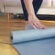 Woman Rolls Yoga Mat on Wooden Board Floor After Training - VideoHive Item for Sale