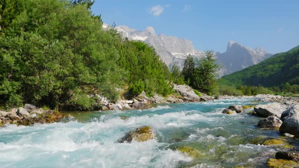 Rapid Mountain River Water with Majestic Rocky Mountains at Background