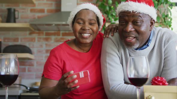 Happy african american senior couple in santa hats on video call at christmas time