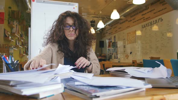 Tired Businesswoman in the Office with Stack of Papers