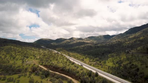 Aerial Panorama of cars driving on highway through green California mountains