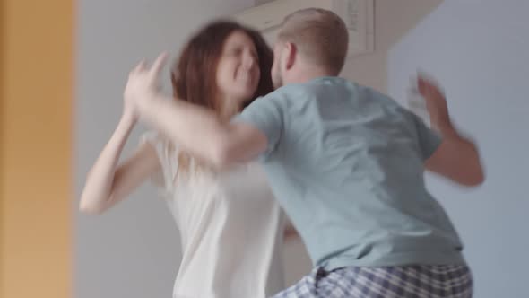 Caucasian Couple Jumping on Bed and Pretending to Quarrel