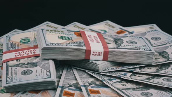 Bundles of Dollars Lying on a Pile of Money and Rotate on Black Background