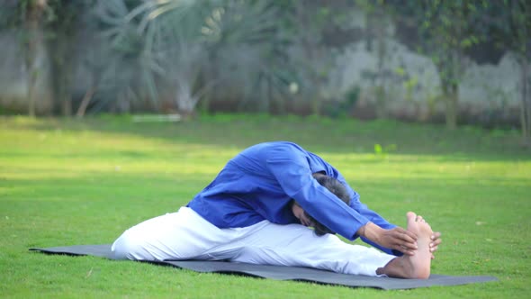 Indian man doing Folded leg forward bend yoga or Triang Mukha Eka Pada Paschimottanasana