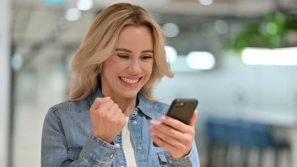 Young Casual Woman Celebrating Success on Smartphone 