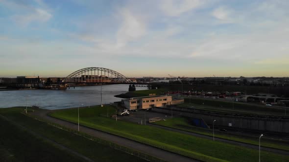 Drone pan shot of vehicles driving into a tunnel underneath a river while cars driving on a bridge a