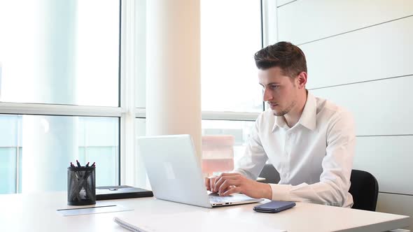 Young businessman indoor office interior using laptop computer and smart phone