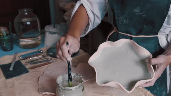 Professional Potter Decorating and Painting a Dish After She Has Baked It in the Kiln