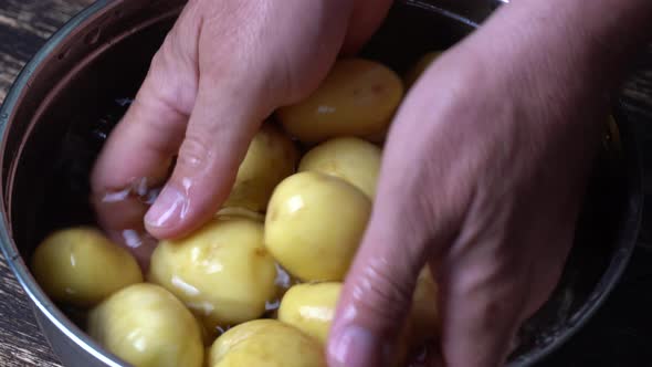 Cook washes young potatoes in water in a metal pan