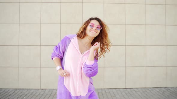 Funny cheerful happy young woman dancing outdoors on yellow wall